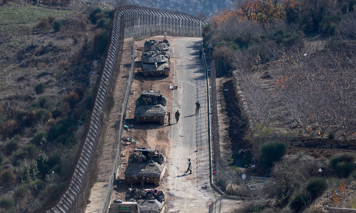 Israeli tanks and armored vehicles line up the area outside the Druze village of Majdal Shams on the fence with the buffer zone that separates the Israeli-annexed Golan Heights from the rest of Syria on December 9, 2024. Photo: AFP