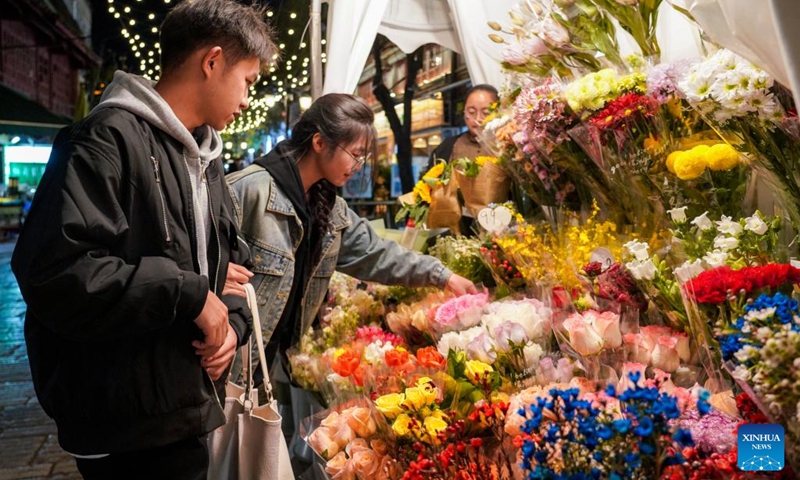 Tourists select flowers on a street at night in Kunming City, southwest China's Yunnan Province, Dec. 6, 2024. In recent years, Kunming has stepped up its efforts to enrich citizen's life by developing night fair compounds. Photo: Xinhua