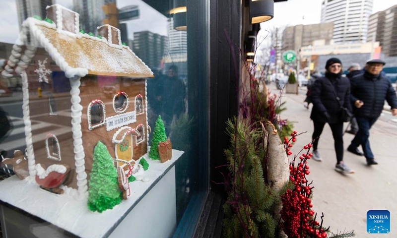 People walk past a shop window displaying a gingerbread house during the 2024 Toronto Gingerbread Festival in Toronto, Canada, on Dec. 8, 2024. The week-long event is held here from Dec. 3 to 10, showcasing 16 professionally-designed gingerbread houses at select storefront windows. Photo: Xinhua