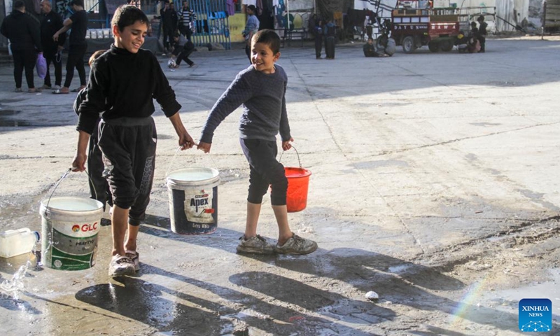 Displaced Palestinian children carry buckets of water in a shelter in Gaza City on Dec. 9, 2024. (Photo:Xinhua)