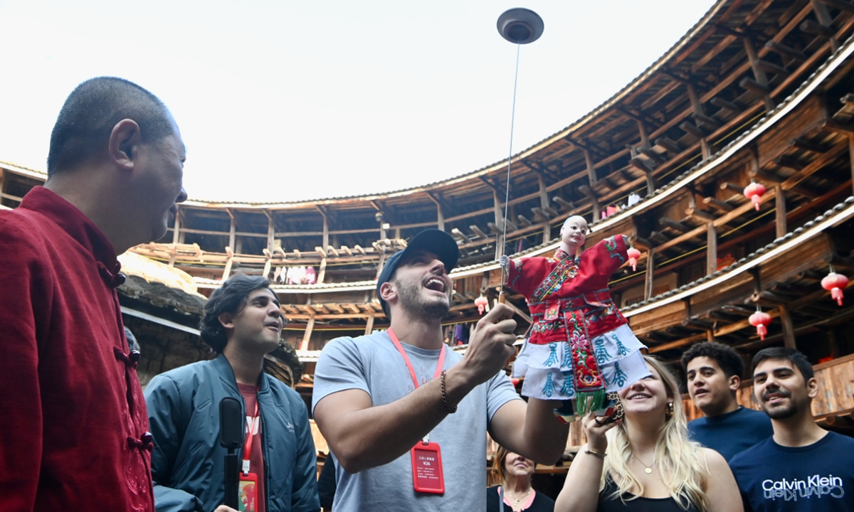 Foreign students learn about hand puppet performances inside a Tulou in Nanjing county, East China's Fujian Province, on December 11, 2024. Fujian Tulou, which dates back to the Song (960-1279) and Yuan (1279-1368) dynasties, are circular fortress-like Chinese rural dwellings built by the Hakka people in the mountainous areas of Fujian. Photo: VCG