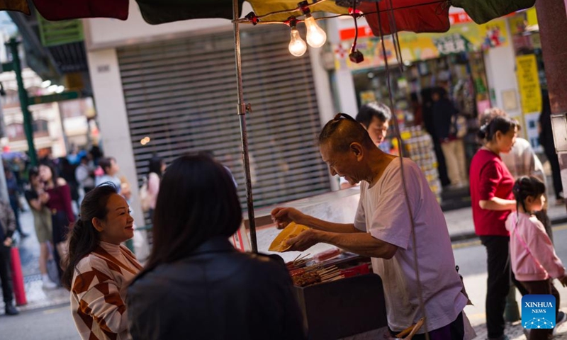 A roast shop worker talks with a customer in Macao, south China, Dec. 8, 2024. (Photo: Xinhua)