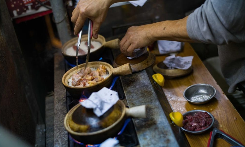 A worker cooks clay pot rice in Macao, south China, Dec. 8, 2024. (Photo: Xinhua)