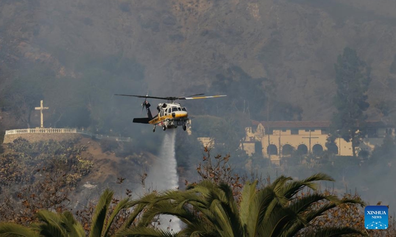 A firefighting helicopter drops water on the wildfire in Malibu, California, the United States, Dec. 10, 2024. (Photo: ecns.cn)