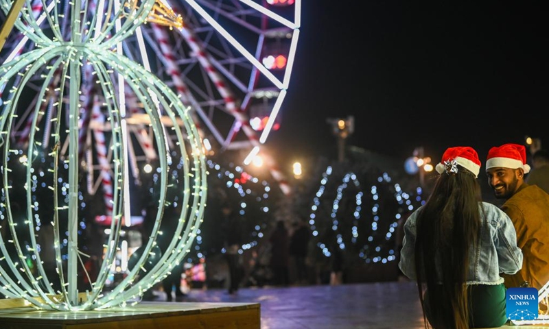 People sit by a light decoration at a Christmas fairyland in Valletta, Malta, on Dec. 10, 2024. (Photo: Xinhua)