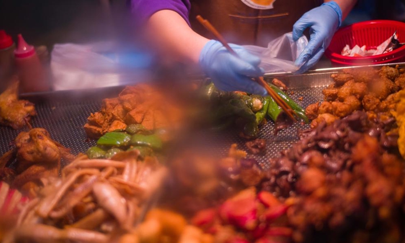 A food stall worker packs snacks for customers in Macao, south China, Dec. 8, 2024. (Photo: Xinhua)