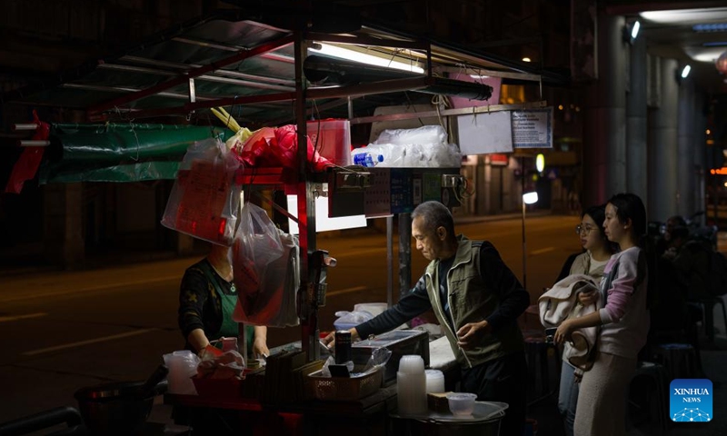 A food stall worker packs sweet for customers in Macao, south China, Dec. 8, 2024. (Photo: Xinhua)