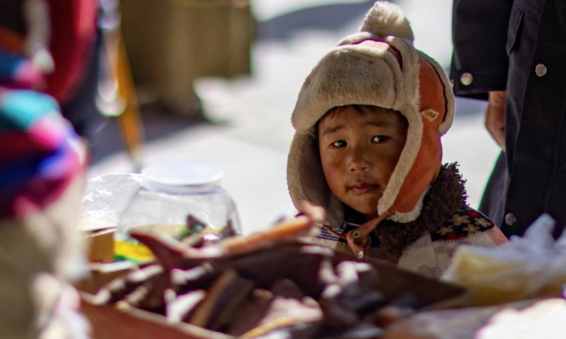 A child is pictured at a trading fair at the Singpori relocation site in Shannan, southwest China's Xizang Autonomous Region, Dec. 17, 2024. A six-day trading fair kicked off on Tuesday at the Singpori relocation site, which is home to more than 30,000 relocated residents.

Singpori sits on the north bank of the Yarlung Zangbo River in the city of Shannan, at an altitude of 3,600 meters. (Xinhua/Jiang Fan)