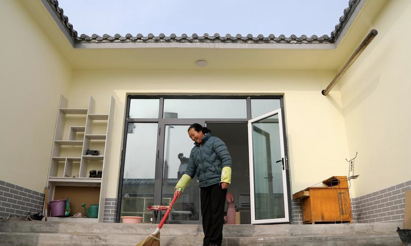 Villager Ji Fangfang cleans the courtyard in a resettlement area in Liuji Township of Jishishan County, northwest China's Gansu Province, Dec. 11, 2024. (Xinhua/Ma Sha)