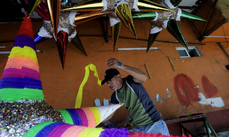 A man makes a pinata in Mexico City, Mexico, Dec. 13, 2024. Pinata, traditionally crafted in the shape of a seven-pointed star, is filled with candies and small gifts, bringing joy and festive spirit to celebrations. (Xinhua/Francisco Canedo)