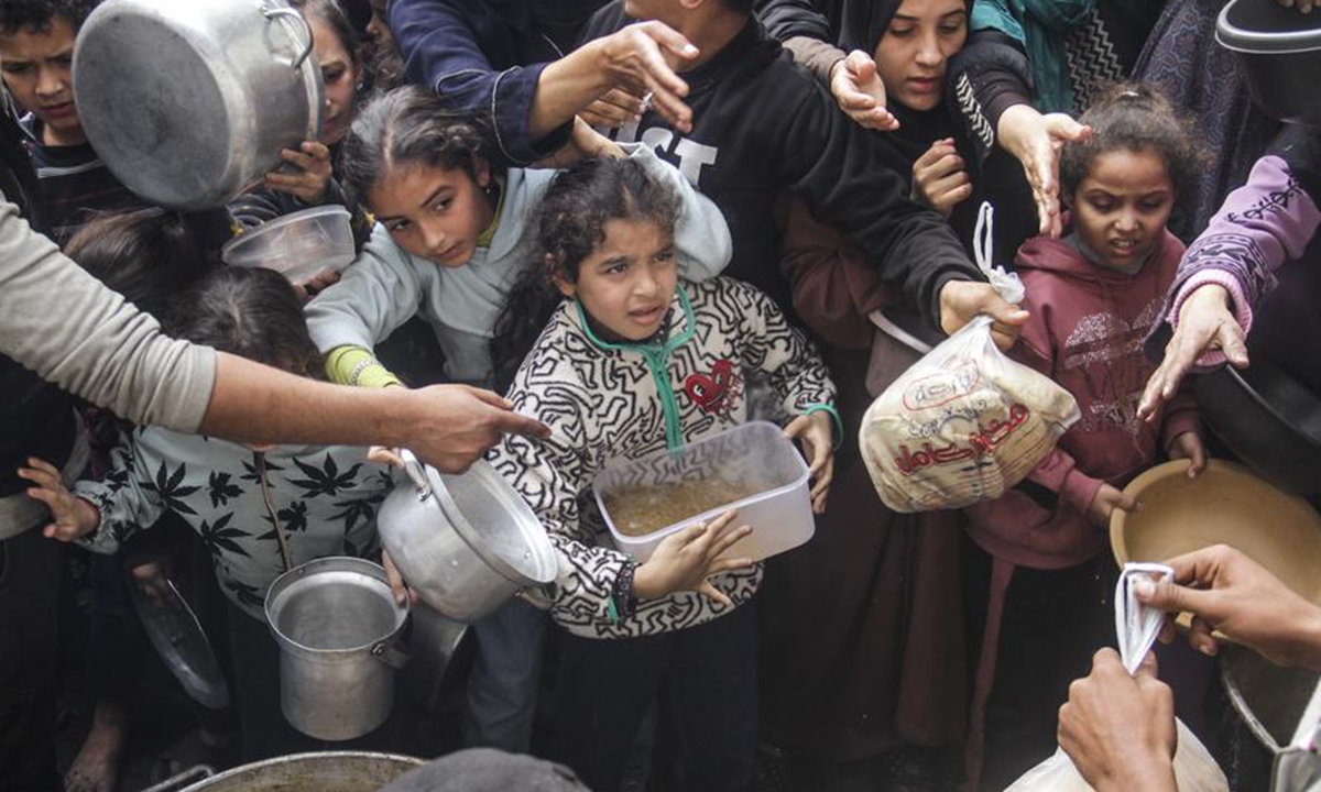 Displaced Palestinians try to get food aid from a local community kitchen amid the siege imposed by the Israeli army and the scarcity of aid in the Al-Shati camp, west of Gaza City, on Dec. 7, 2024. (Photo: Xinhua)