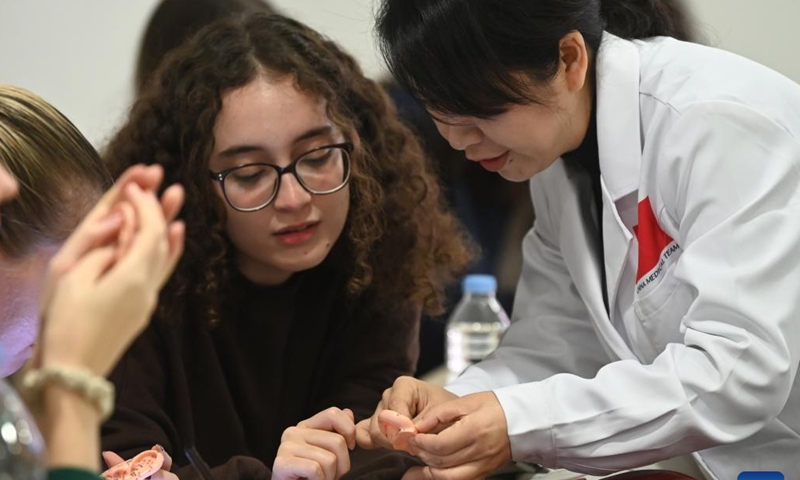 Tang Limei (R), a member of the 20th Chinese medical team for Malta, explains auricular acupoints to students at the University of Malta in Msida, Malta, on Dec. 11, 2024.  (Photo: Xinhua)