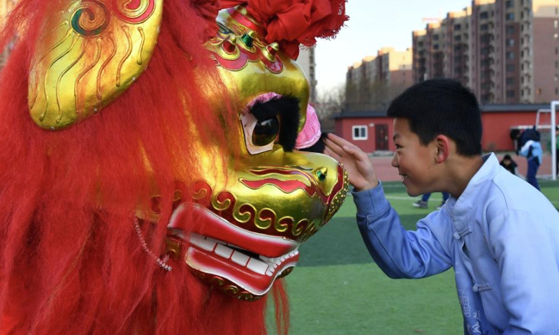 A student interacts with a lion dancer from Cangxian County at a primary school in Cangzhou City, north China's Hebei Province, Dec. 20, 2024. Cangxian Lion Dance is a unique folk art with a long history, which was inscribed into the national intangible cultural heritage list in 2008. Thanks to the policy and funding support of local authorities in recent years, the traditional art has been well passed on. There are nine registered lion dance teams and nearly 1,000 performers in the county. (Xinhua/Mu Yu)