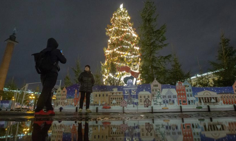 A visitor takes photos in front of an illuminated new year tree at Palace Square in St. Petersburg, Russia, Dec. 20, 2024. (Photo by Irina Motina/Xinhua)