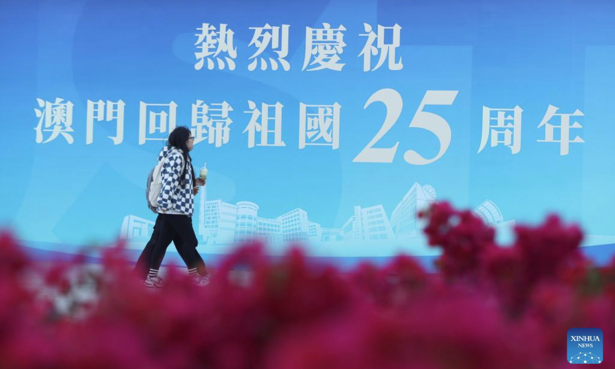 A pedestrian walks past a celebration poster at Macao University of Science and Technology in Macao, south China, Dec. 17, 2024. The streets of Macao have been adorned by festive decorations, as the city is set to mark the 25th anniversary of its return to the motherland. (Xinhua/Yao Qilin)