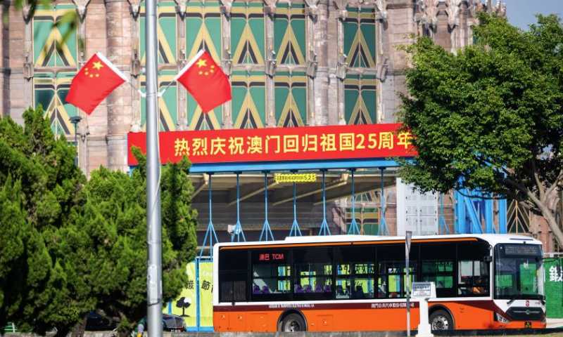 Vehicles pass by a celebration banner in Macao, south China, Dec. 17, 2024. The streets of Macao have been adorned by festive decorations, as the city is set to mark the 25th anniversary of its return to the motherland. (Xinhua/Zhu Wei)