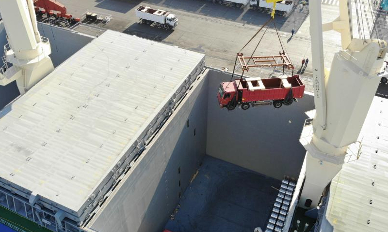 An aerial drone photo taken on Dec. 16, 2024 shows an engineering vehicle being loaded onto the cargo ship GREEN NAGOYA at Qingdao Port in Qingdao, east China's Shandong Province. The vessel is expected to arrive at the Dar es Salaam Port in Tanzania in about 20 days. A new direct shipping route between China's Qingdao and southeast Africa was officially opened on Monday. Running on a weekly basis, this route adds a safe and fast maritime shipping alternative between China and Africa. (Xinhua/Li Ziheng)