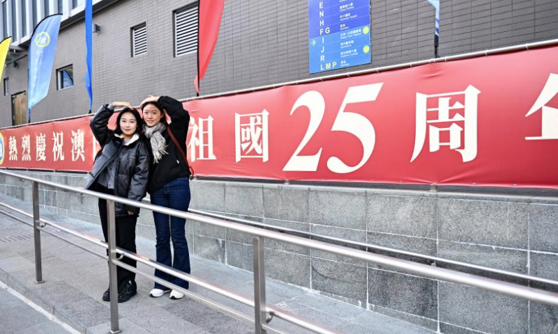 Students pose for photos in front of a celebration banner at the Macao University of Science and Technology in Macao, south China, Dec. 18, 2024. The streets of Macao have been adorned by festive decorations, as the city is set to mark the 25th anniversary of its return to the motherland. (Xinhua/Cheng Yiheng)