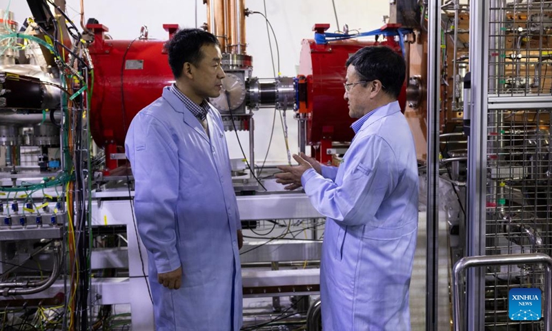 Zhao Hongwei (R), an academician of the Chinese Academy of Sciences (CAS), and Sun Liangting, a researcher with the Institute of Modern Physics of the CAS, discuss on experiment progress in front of the low-energy high-intensity heavy-ion accelerator facility (LEAF) on Dec. 10, 2024. (Photo: Xinhua)