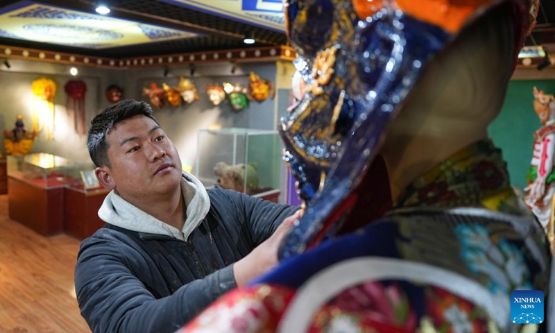 A craftsman looks at traditional Tibetan masks at a cooperative in Dagze District of Lhasa, southwest China's Xizang Autonomous Region, Dec. 9, 2024. (Photo: Xinhua)