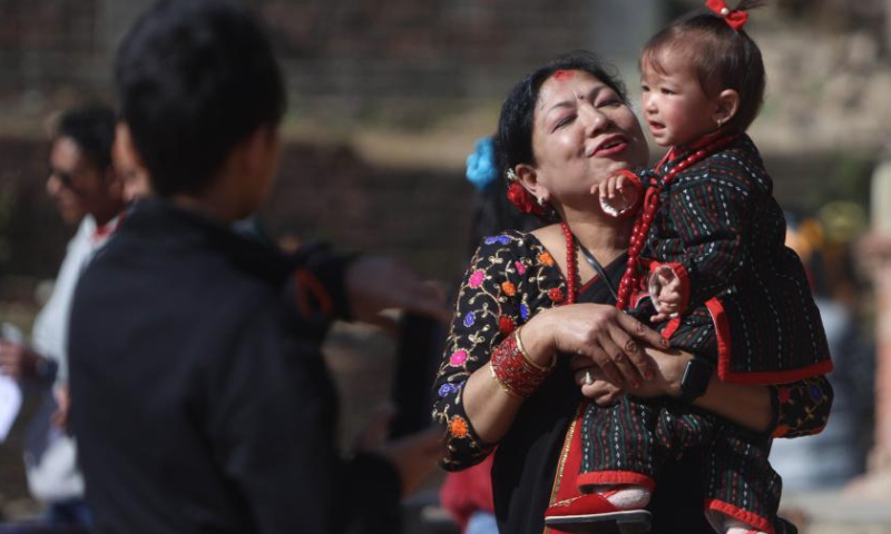 A woman carrying a girl joins a rally to celebrate Yomari Punhi in Kathmandu, Nepal, Dec. 15, 2024. Yomari Punhi is a festival especially celebrated by Newar community in Nepal to mark the end of the rice harvest on full moon day. (Photo by Sulav Shrestha/Xinhua)