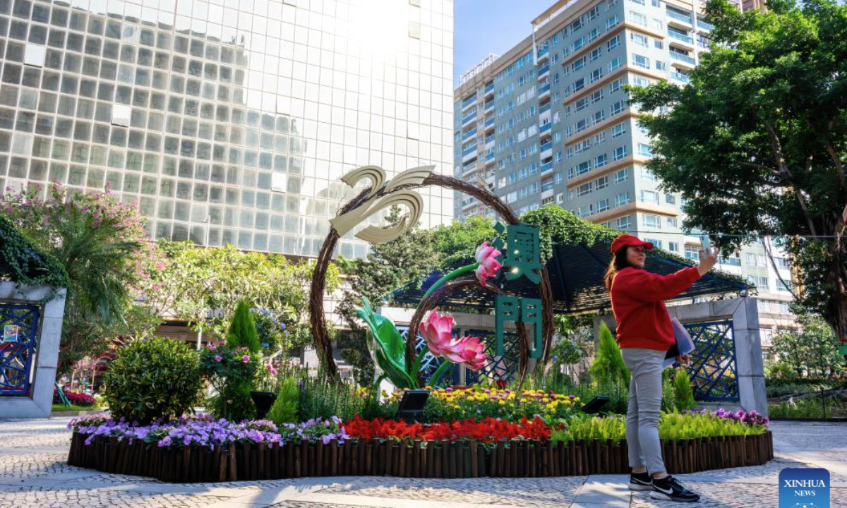 A woman takes selfies in front of a celebration installation in Macao, south China, Dec. 17, 2024. The streets of Macao have been adorned by festive decorations, as the city is set to mark the 25th anniversary of its return to the motherland. (Xinhua/Zhu Wei)