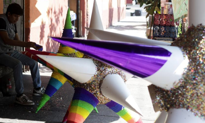 A man makes a pinata in Mexico City, Mexico, Dec. 13, 2024. Pinata, traditionally crafted in the shape of a seven-pointed star, is filled with candies and small gifts, bringing joy and festive spirit to celebrations. (Xinhua/Francisco Canedo)