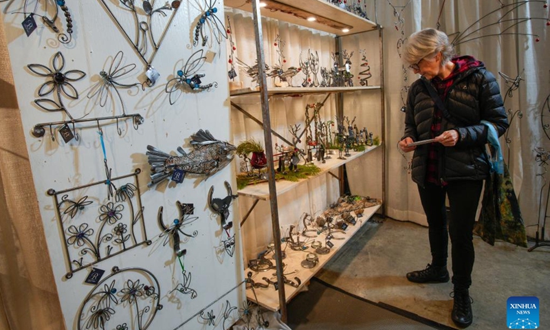 A woman looks at handmade ornaments at a vendor's booth during the annual Make It Show in Vancouver, British Columbia, Canada, Dec. 12, 2024. The annual event showcases a diverse array of handmade goods from over 250 artists, makers and craftsmen. (Photo by Liang Sen/Xinhua)