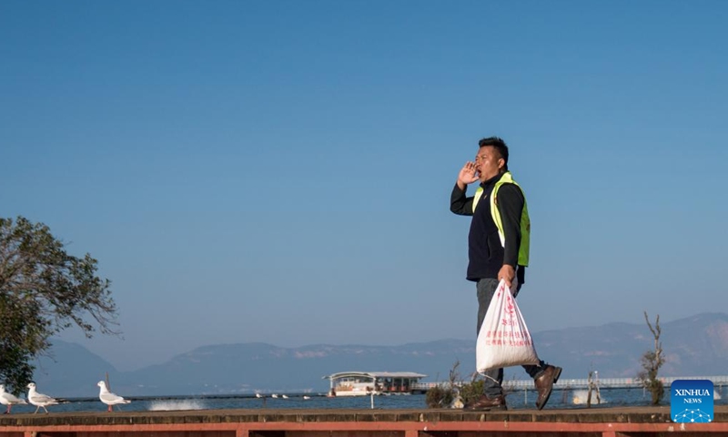 Zhang Liyun prepares to feed black-headed gulls at the Wangguan wetland park by the Dianchi Lake in Kunming, southwest China's Yunnan Province, Dec. 11, 2024.(Photo by Peng Yikai/Xinhua)