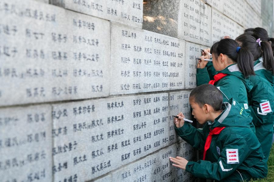 Students use black pens to renew the names on the wailing wall outside the Memorial Hall of the Victims in Nanjing Massacre by Japanese Invaders in Nanjing, east China's Jiangsu Province, Dec. 1, 2024. (Xinhua/Li Bo)