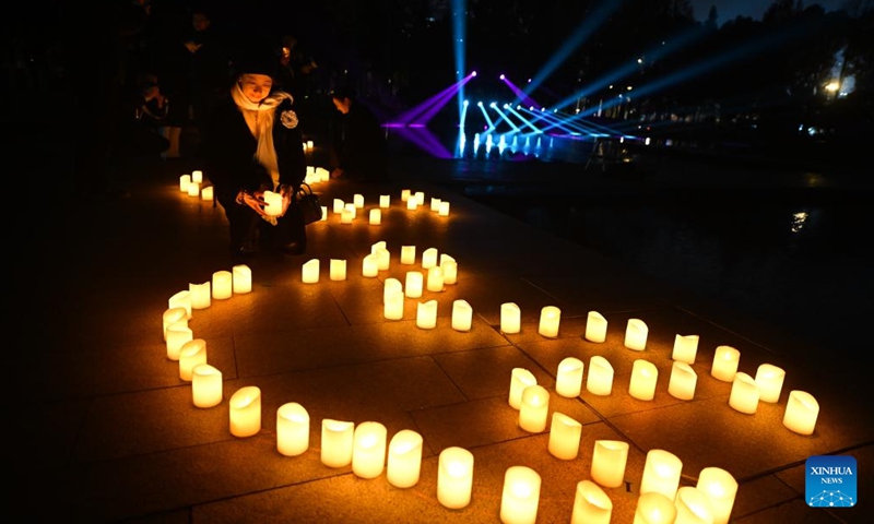 A woman places a candle while attending a candle light vigil at the Memorial Hall of the Victims in Nanjing Massacre by Japanese Invaders in Nanjing, capital of east China's Jiangsu Province, Dec. 13, 2024. (Photo: Xinhua)