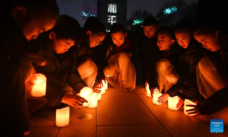 Children place candles while attending a candle light vigil at the Memorial Hall of the Victims in Nanjing Massacre by Japanese Invaders in Nanjing, capital of east China's Jiangsu Province, Dec. 13, 2024. A candle light vigil was held here on Friday to mark this year's national memorial day for the victims of the Nanjing Massacre. (Photo: Xinhua)