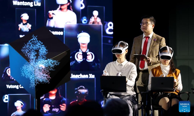 People participate in a demonstration of smart education showcasing a scenario of a future computational biology class using AI, digital twin and virtual reality (VR) technologies, during an international conference on online education and massive open online courses (MOOC) in London, Britain, on Dec. 12, 2024. (Photo: Xinhua)