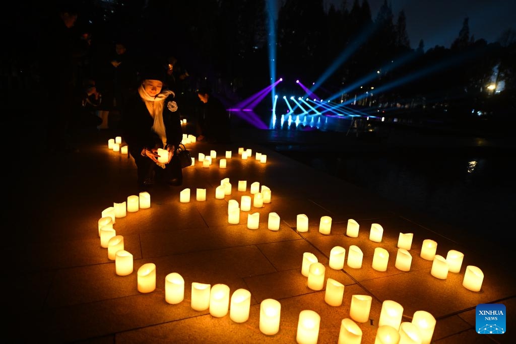 A woman places a candle while attending a candle light vigil at the Memorial Hall of the Victims in Nanjing Massacre by Japanese Invaders in Nanjing, capital of east China's Jiangsu Province, Dec. 13, 2024. A candle light vigil was held here on Friday to mark this year's national memorial day for the victims of the Nanjing Massacre. (Photo: Xinhua)