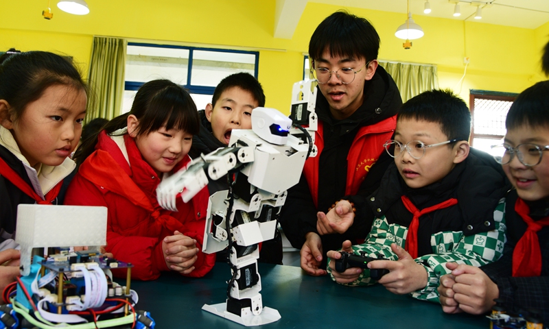 Volunteers from Jiangsu University teach students the functions of a humanoid robot at a primary school in Zhenjiang city, East China's Jiangsu Province on December 18, 2024. Photo: VCG