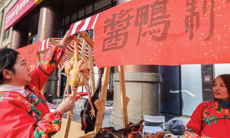 Staff members work at a stall selling traditional food at a New Year fair in Shangcheng District of Hangzhou, east China's Zhejiang Province, Dec. 31, 2024. The fair opened here on Tuesday, with themed sections showcasing intangible cultural heritage, cultural and creative products, folk custom, and folk arts native to Hangzhou. Specialty food and deli are also made available there, adding a festive atmosphere to the city. (Xinhua/Xu Yu)