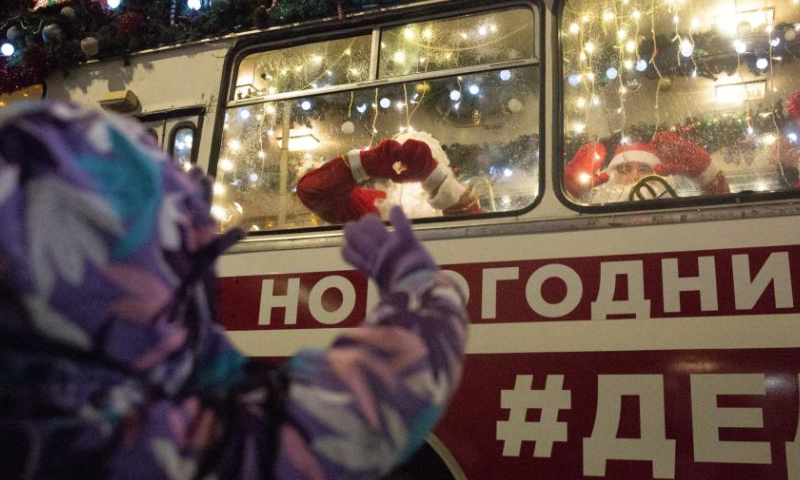 A musician dressed as Father Frost makes a heart gesture to a kid in St. Petersburg, Russia, Dec. 25, 2024. Musicians in holiday costumes took a holiday bus around the Russian city to play music and distribute gifts to citizens in celebration of the upcoming New Year. (Photo by Irina Motina/Xinhua)