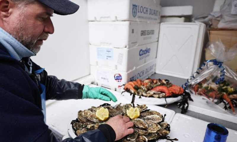 A staff member prepares a seafood platter at Maree d'Auteuil, a seafood stall, ahead of Christmas eve in Paris, France, Dec. 24, 2024. (Xinhua/Gao Jing)