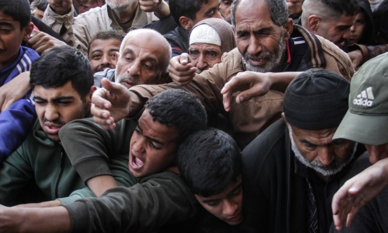 Children try to receive food relief at a food distribution center in Gaza City, on Dec. 23, 2024. (Photo by Mahmoud Zaki/Xinhua)