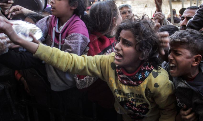 Children try to receive food relief at a food distribution center in Gaza City, on Dec. 23, 2024. (Photo by Mahmoud Zaki/Xinhua)