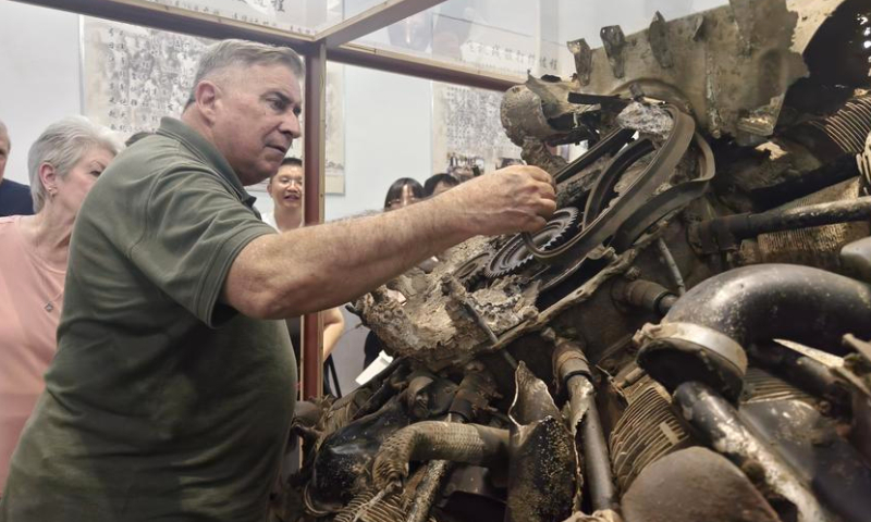 Jeffrey Greene, chairman of the Sino-American Aviation Heritage Foundation, has a touch of the wreckage from Flying Tigers bombers displayed at an exhibition in Huimin Village in Anqing City, east China's Anhui Province, Sept. 10, 2024. (Xinhua/Guo Chen)