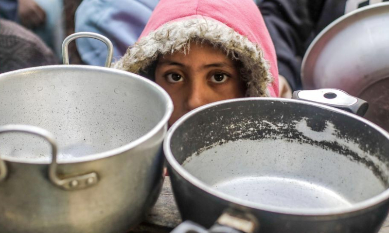 A Palestinian waits for receiving free food from a food distribution center in Gaza City, on Dec. 27, 2024. (Photo by Mahmoud Zaki/Xinhua)