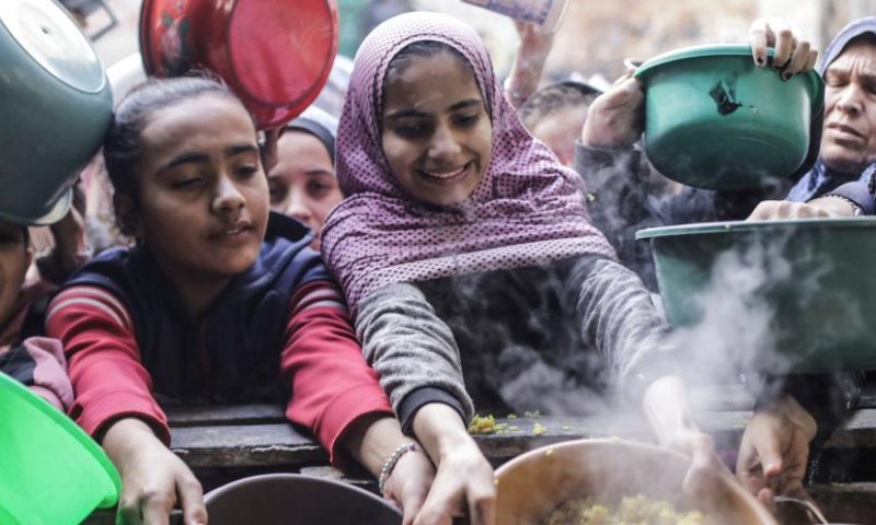 Palestinians receive free food from a food distribution center in Gaza City, on Dec. 27, 2024. (Photo by Mahmoud Zaki/Xinhua)