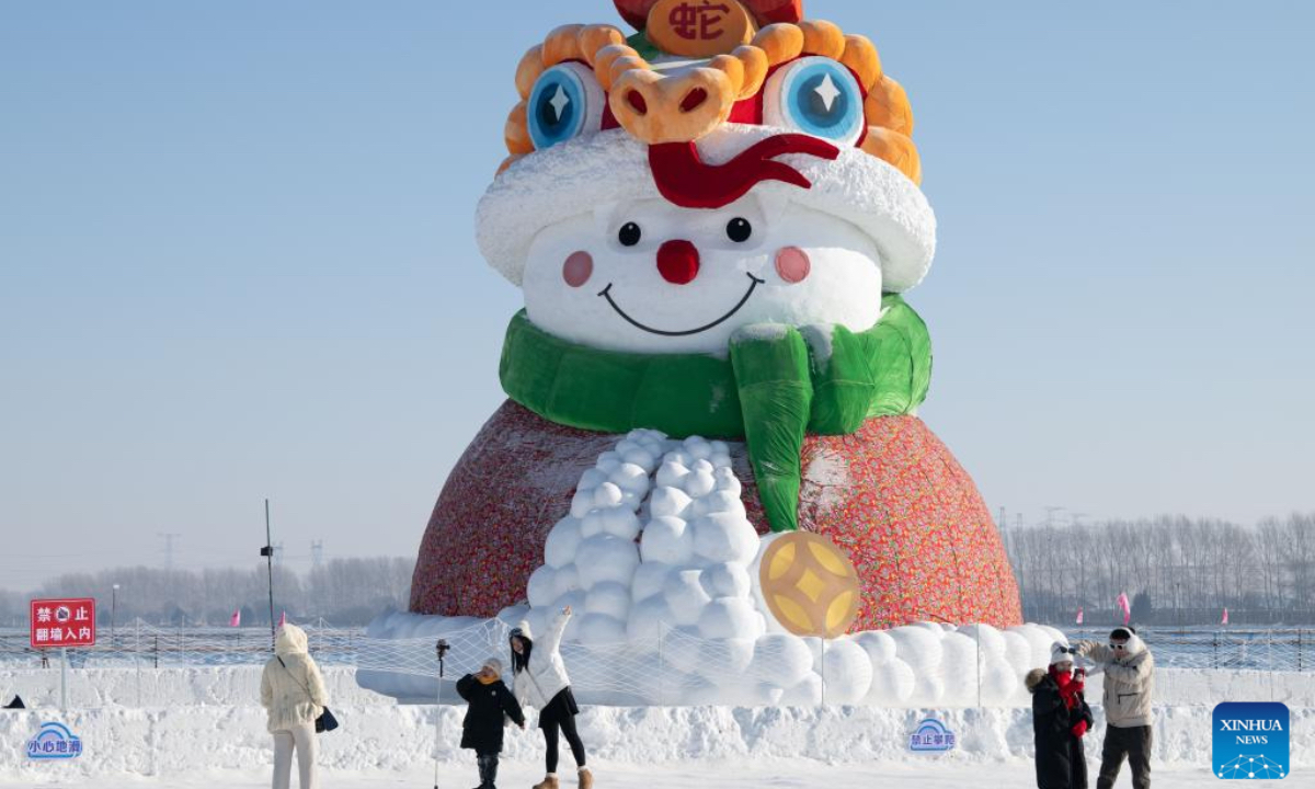 People pose for photos with a snowman at a farm of Beidahuang Group in Harbin, capital of northeast China's Heilongjiang Province, Jan. 4, 2025. Harbin, with many snow sculptures across the city, has emerged as one of China's top winter travel destinations, attracting tourists from around the globe. (Photo: Xinhua)