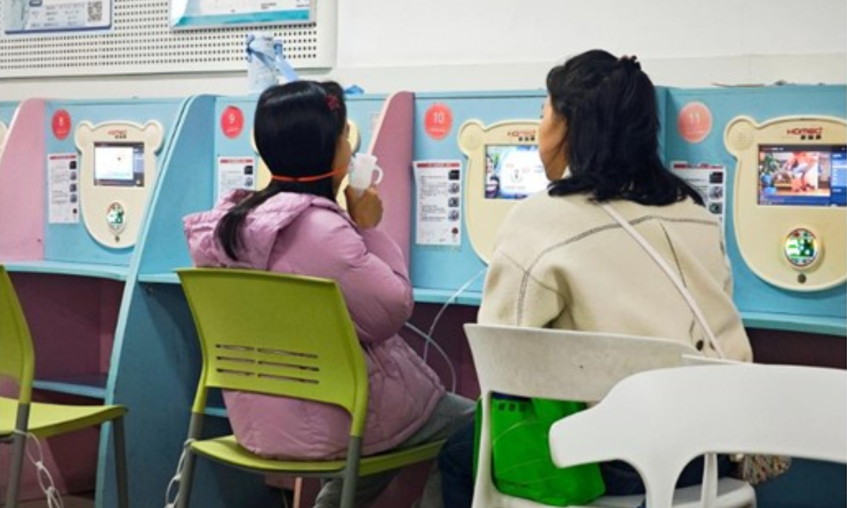 A child accompanied by her parent receives nebulization treatment. Photo: Xinhua