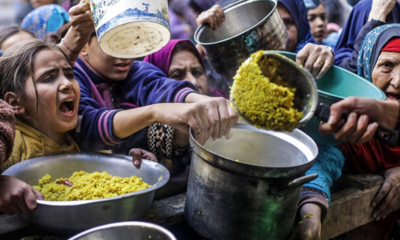 Palestinians receive free food from a food distribution center in Gaza City, on Dec. 27, 2024. (Photo by Mahmoud Zaki/Xinhua)