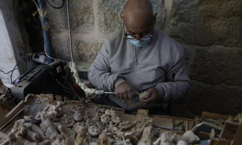 A craftsman works at a workshop in the West Bank city of Bethlehem, Dec. 23, 2024. Revered as the site of Jesus Christ's birth, Bethlehem sees a muted Christmas season this year as tourists stay away amid the Israeli ongoing attacks on the Gaza Strip. (Photo by Mamoun Wazwaz/Xinhua)