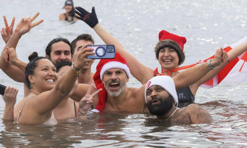 Participants pose for a selfie in Lake Ontario during the Toronto Polar Bear Dip event in Toronto, Canada, on Jan. 1, 2025. Hundreds of people braved the chilly waters here on Wednesday to celebrate the first day of 2025 and raise funds for charity. (Photo by Zou Zheng/Xinhua)