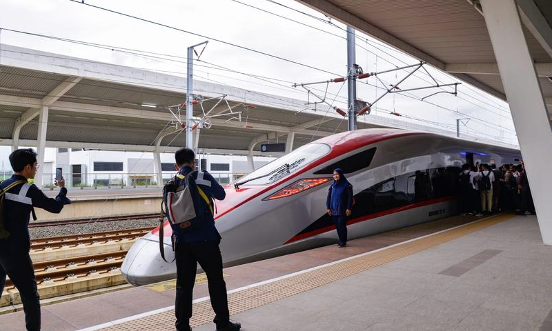 A passenger poses for photos with a high-speed electrical multiple unit (EMU) train on the platform of Karawang Station of Jakarta-Bandung High-Speed Railway in West Java, Indonesia, Dec. 24, 2024. (Xinhua/Xu Qin)