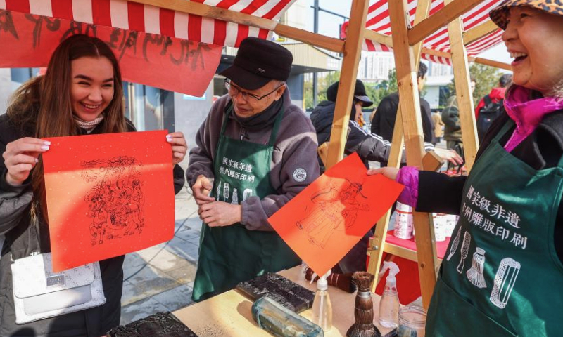 A foreign student (1st L) tries block printing at a New Year fair in Shangcheng District of Hangzhou, east China's Zhejiang Province, Dec. 31, 2024. The fair opened here on Tuesday, with themed sections showcasing intangible cultural heritage, cultural and creative products, folk custom, and folk arts native to Hangzhou. Specialty food and deli are also made available there, adding a festive atmosphere to the city. (Xinhua/Xu Yu)